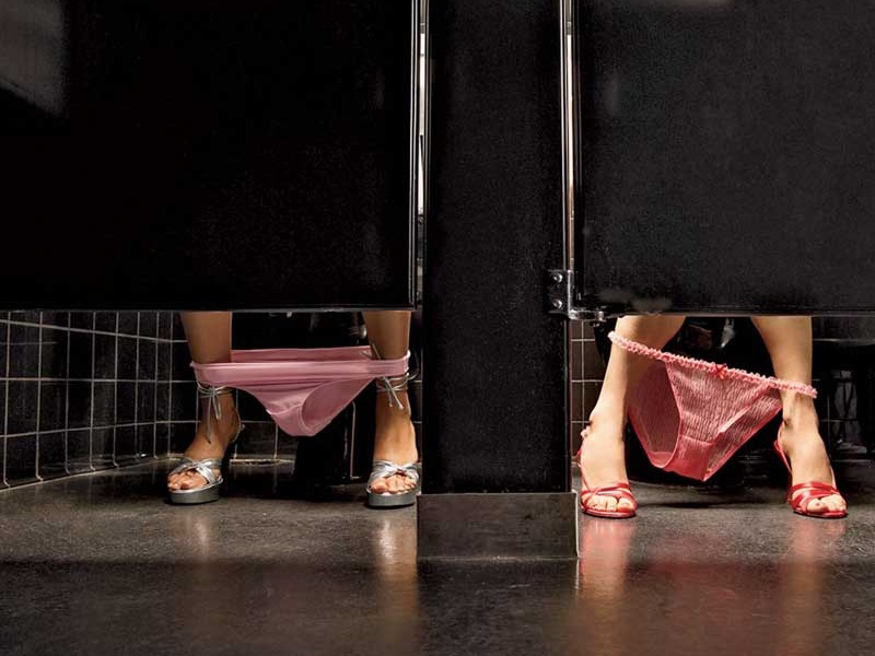 Women with underwear around ankles in restroom stalls